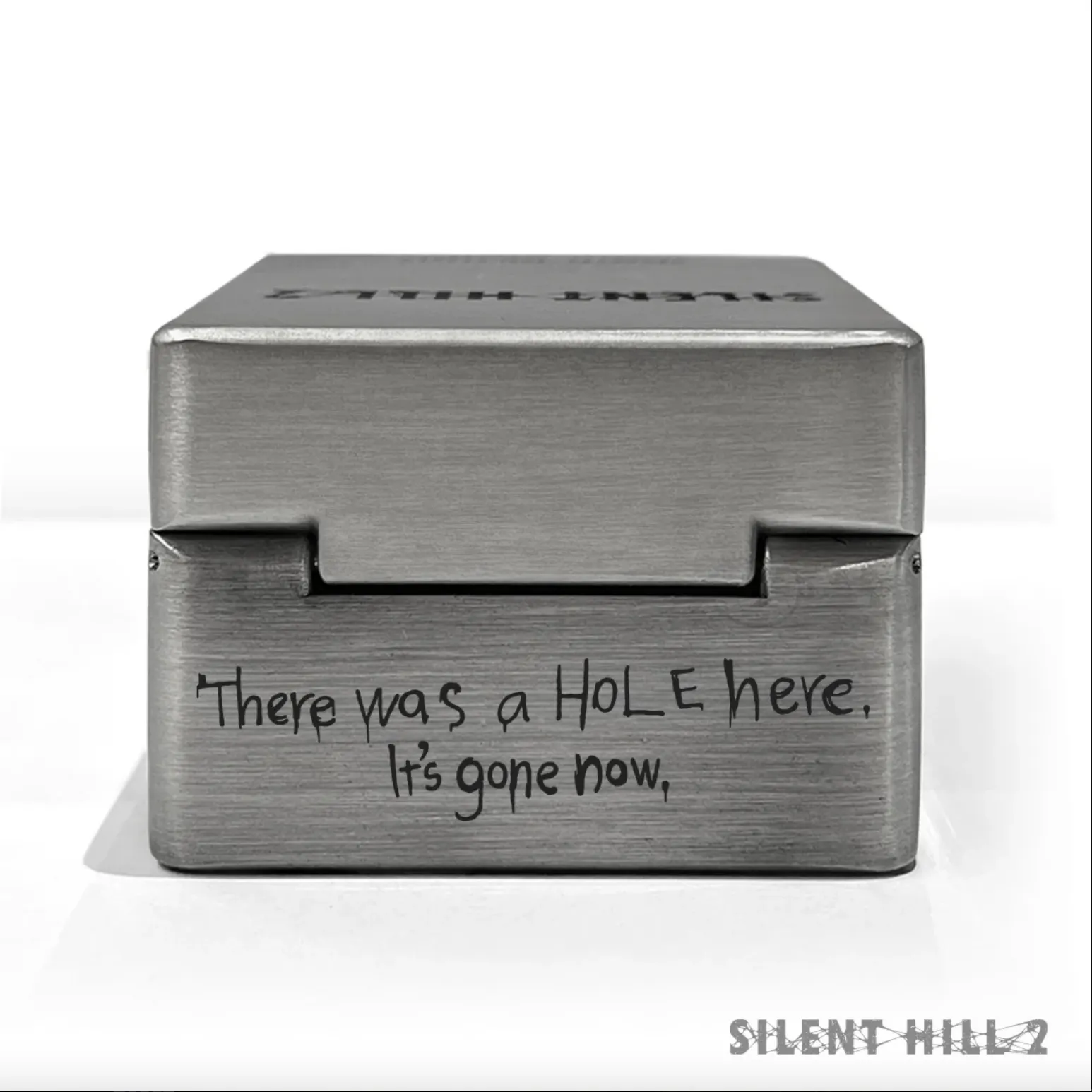 Caja de música de metal de Silent Hill 2 que presenta un grabado que dice